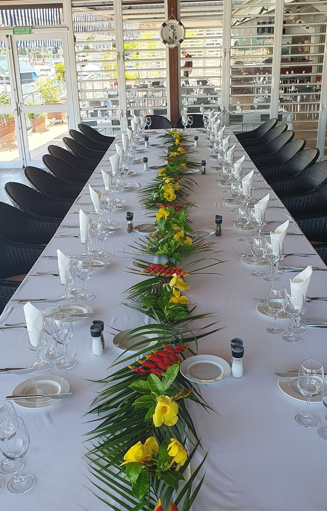 Une grande table dressée pour un banquet, décorée de fleurs tropicales